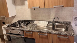 Een moderne keuken met granieten aanrechtbladen, roestvrijstalen apparatuur en houten kastjes.
