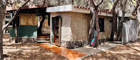 A rustic cabin with a stone exterior, a wooden door, and a covered porch.