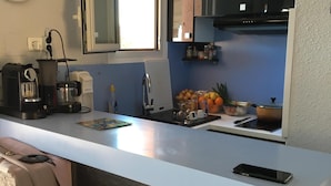 Cocina moderna con encimera blanca, cafetera, hervidor y un teléfono inteligente sobre la encimera.