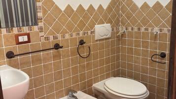 Een badkamer met twee toiletten, een toiletbrons, een wastafel en een spiegel.