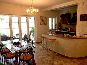 Un coin repas avec une table à plateau en verre, des chaises noires et un lustre.