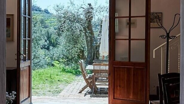 A hallway leading to a patio with a view of a garden and a wooden table.