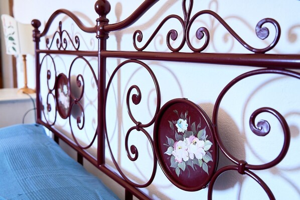 A metal bed frame with ornate designs and a floral decoration on the headboard.