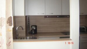 Cozinha com armários brancos, pia de aço inoxidável e cafeteira.