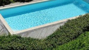 A rectangular swimming pool with clear blue water, surrounded by a wooden deck and lush greenery. - Country Cottage / Gite - LA ROQUE GAGEAC (La Roque-Gageac)