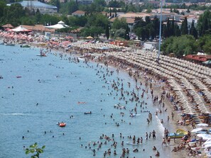 A crowded beach with numerous people, umbrellas, and boats.