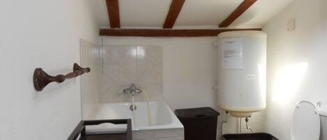 A small bathroom with a bathtub, toilet, and a water heater.