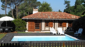 A house with a tiled roof, a swimming pool, and outdoor furniture.