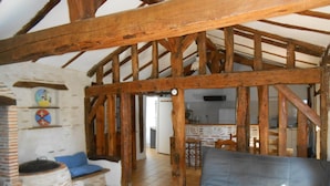A rustic interior with exposed wooden beams, a brick oven, and a sofa.