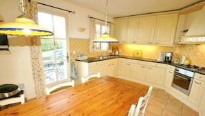 A kitchen with a wooden table, white cabinets, and a tiled backsplash.