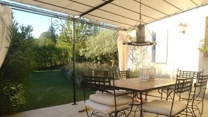 An outdoor patio with a table and chairs, surrounded by a garden view.
