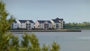 A row of multi-story residential buildings with balconies, situated by a body of water.