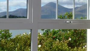 A window with a view of mountains and a body of water.