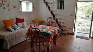 A cozy room with a bed, a dining table, and a staircase. - Seaside holiday home in Bonassola, Madonnina della Punta, near Cinque Terre (bonassola)