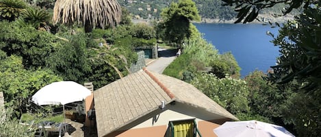 A villa with a tiled roof, outdoor seating, and a view of the sea.