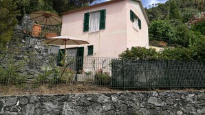 A pink building with green shutters, a stone wall, and a metal fence. - Seaside holiday home in Bonassola, Madonnina della Punta, near Cinque Terre (bonassola)