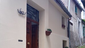 A building with a wooden door, a small window, and a potted plant on the wall. - German house at the Borgo (Badolato)