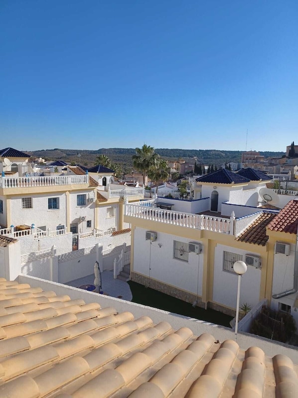 Zona residencial con edificios blancos, cielo azul despejado y vistas a colinas distantes.