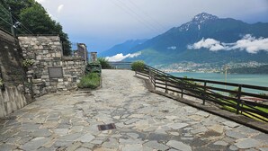 A stone-paved pathway with a wooden railing, leading to a scenic overlook with a view of a lake and mountains. - Villa with large garden and super breathtaking panorama, relaxation, peace (vercana)