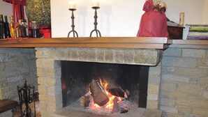 A stone fireplace with a fire burning, a mantel with candles, and a red gift bag on top. - Villa with large garden and super breathtaking panorama, relaxation, peace (vercana)