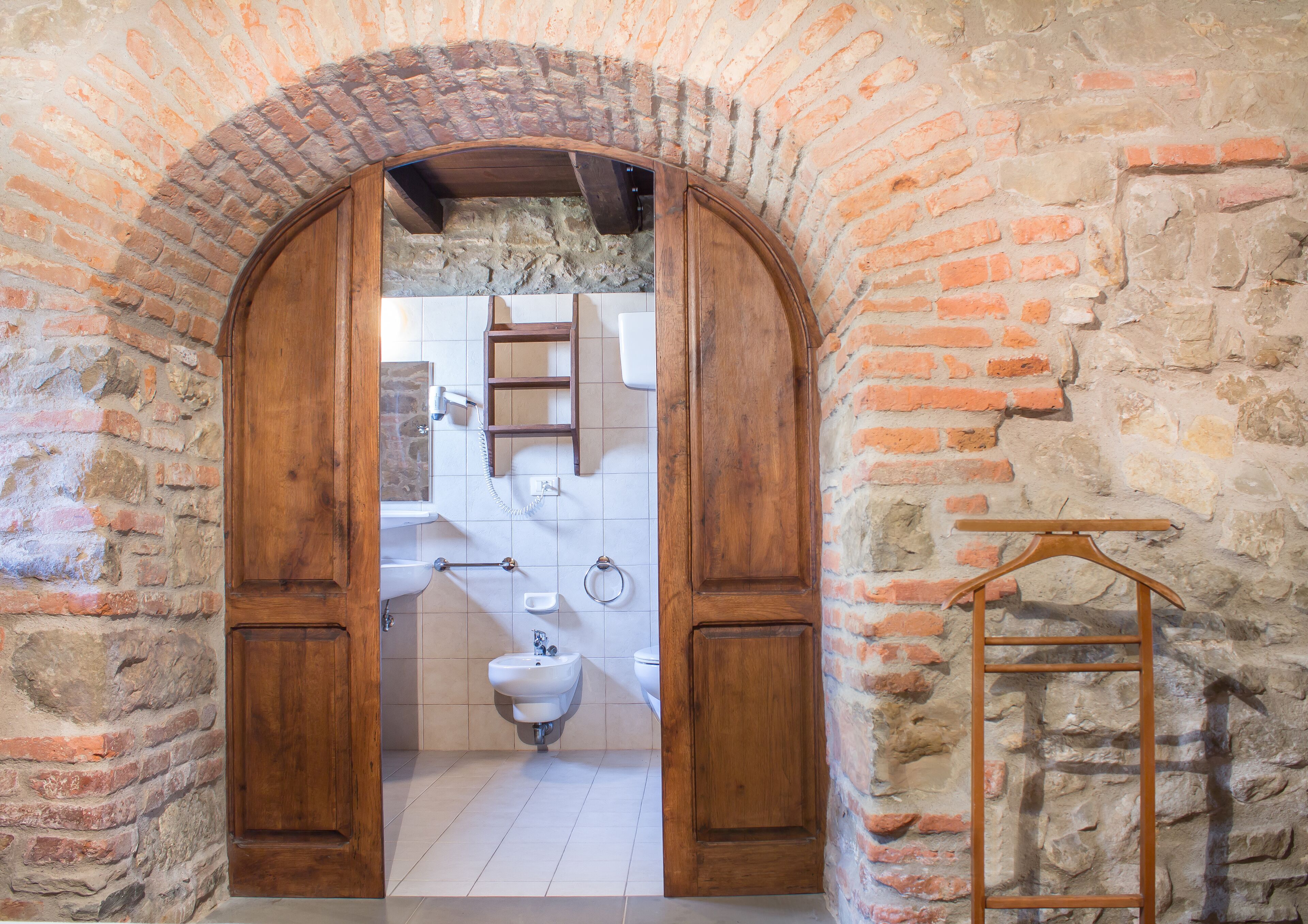 An arched doorway leading to a bathroom with a sink, mirror, and towel rack.