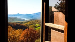 Una finestra con vista su una valle, montagne e un corpo d'acqua.