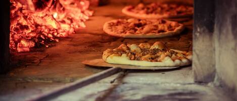 A wood-fired oven with pizzas baking inside.
