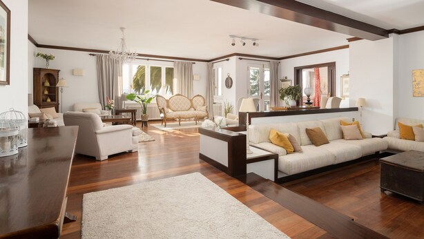 A spacious living room with a wooden floor, a large sofa, a coffee table, and a dining area with a wooden table. - Elegant country house with pool. Between Oviedo and Gijón (Siero)