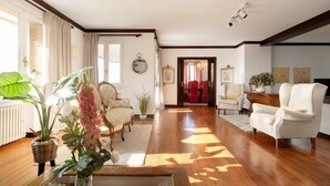 A spacious living room with hardwood flooring, a large window, and a view into another room. - Elegant country house with pool. Between Oviedo and Gijón (Siero)