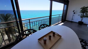 Een balkon met uitzicht op zee, een tafel met een dienblad en een bloempot.