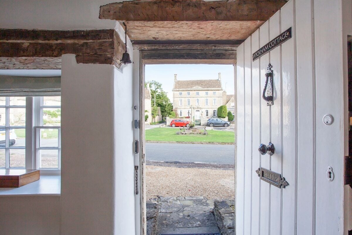 A doorway leading to a street with a sign reading 'WICKHAM COTTAGE'.