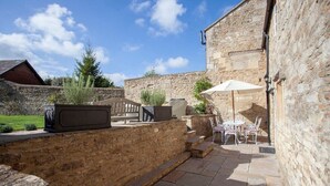 A stone building with a patio area featuring outdoor furniture and a grill. - Charming Country House Nr Bath (WC) (Biddestone)