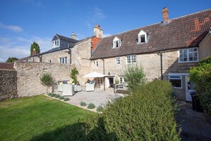 A stone building with a courtyard, outdoor seating, and a well-maintained lawn.
