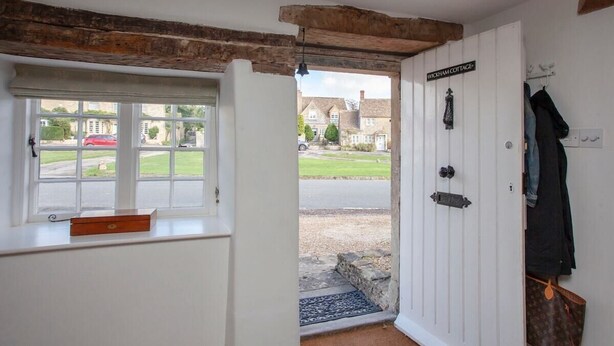 A room with a window, a door labeled 'WICKHAM COTTAGE,' and a coat rack with a bag. - Charming Country House Nr Bath (WC) (Biddestone)