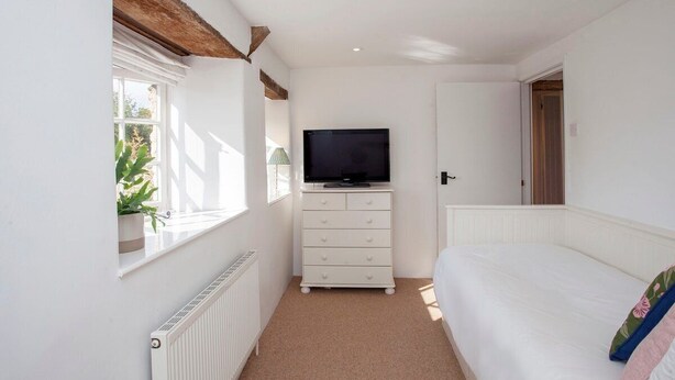 A bedroom with a bed, a dresser, a television, and a window with a plant. - Charming Country House Nr Bath (WC) (Biddestone)