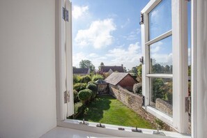 A view from a window of a garden with a brick wall, a small shed, and a lawn.