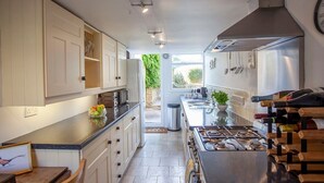 A kitchen with white cabinets, a black countertop, a stove, and a wine rack. - Charming Country House Nr Bath (WC) (Biddestone)