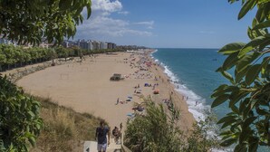 Une plage offrant une vue dégagée sur l’océan, un rivage sablonneux et quelques personnes qui se promènent.