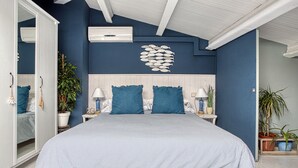 Une chambre à coucher avec un grand lit, un plafond blanc et un climatiseur fixé au mur.