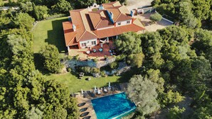 Vista aérea de una casa con piscina, rodeada de abundante vegetación.