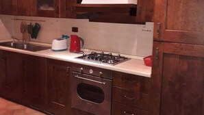 A kitchen with dark wooden cabinets, a stainless steel range, a built-in oven, and a herringbone-patterned floor. - House in Val d'Orcia perfect for relaxation CIN IT052024C2APXZK7PD  (RADICOFANI)