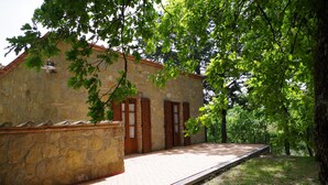 A stone building with a wooden platform, surrounded by trees. - House in Val d'Orcia perfect for relaxation CIN IT052024C2APXZK7PD  (RADICOFANI)