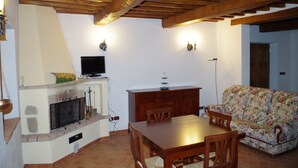 A dining area with a wooden table and chairs, a fireplace, a television, and a sofa. - House in Val d'Orcia perfect for relaxation CIN IT052024C2APXZK7PD  (RADICOFANI)