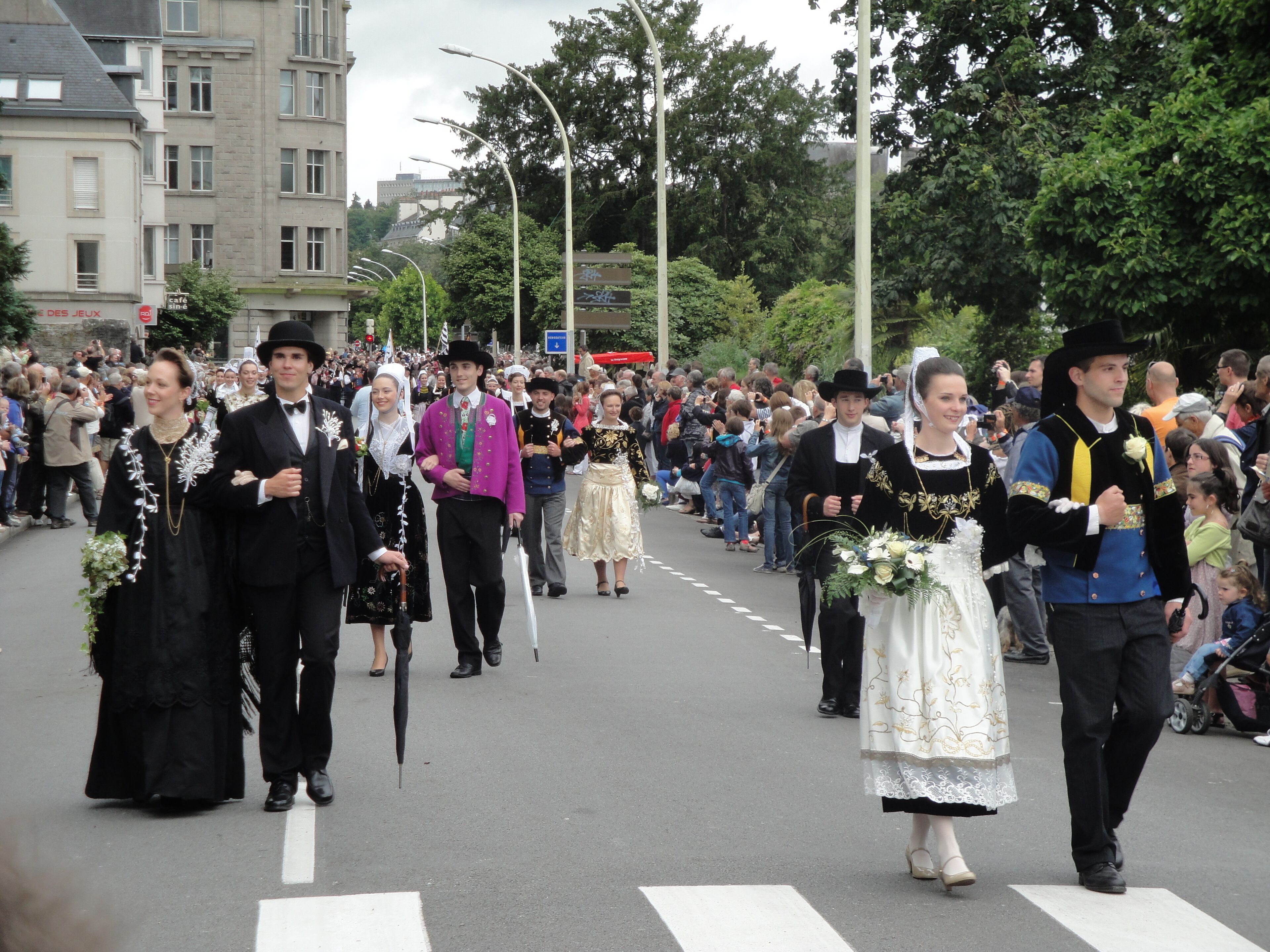 A group of people in traditional costumes walking down a street.