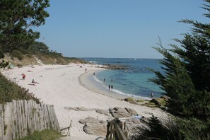 A beach with a wooden walkway leading to the shore, clear skies, and calm waters. - Charming penty, 3* gite, enclosed garden with trees  (Saint-Évarzec)