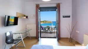 Ein modernes Hotelzimmer mit einem Glastisch, einem Bett, einem Fernseher und einem Balkon mit Meerblick.