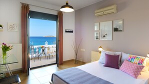 Ein Hotelzimmer mit Bett, Tisch mit Stühlen, Meerblick und einem Balkon mit Tisch und Stühlen.