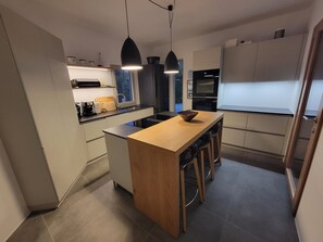 A modern kitchen with a central island, pendant lighting, and a view of the outdoors.