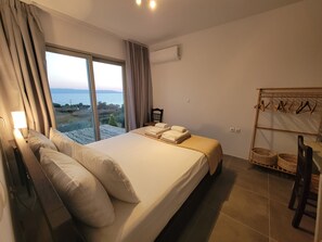 A bedroom with a large bed, a view of the sea, and a drying rack with clothes.