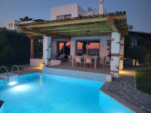 A swimming pool with a pergola and outdoor seating area.